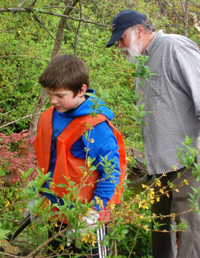 A grandfather and grandson clearing brush