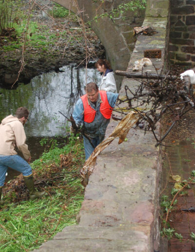 Volunteers clearing sticks near wall